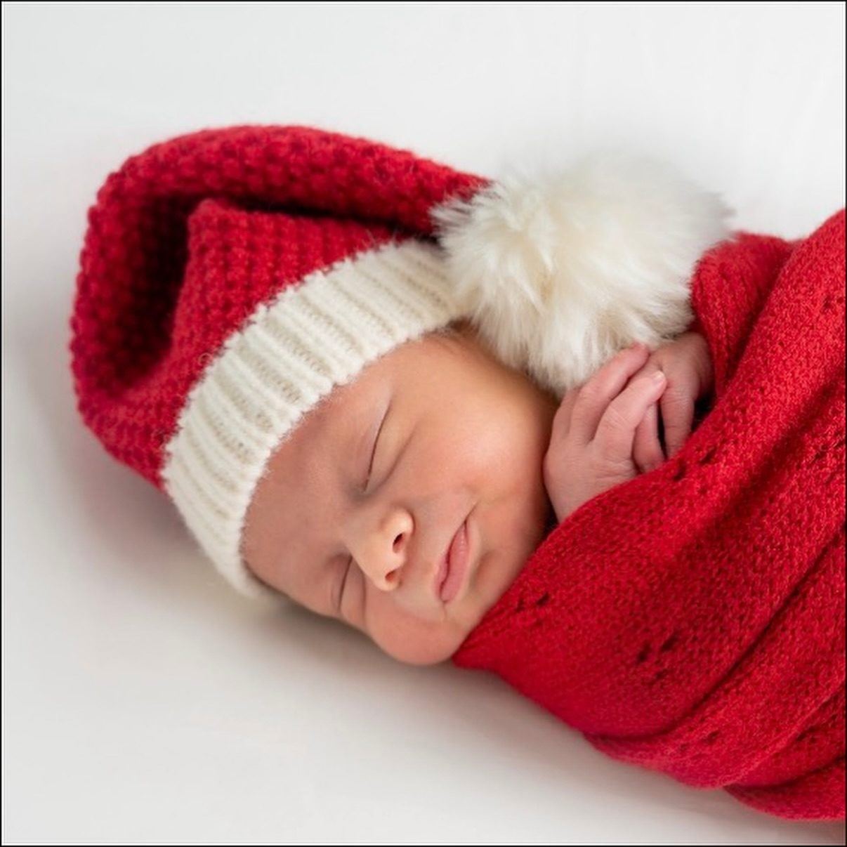Sleeping newborn in a Santa hat and red wrap
